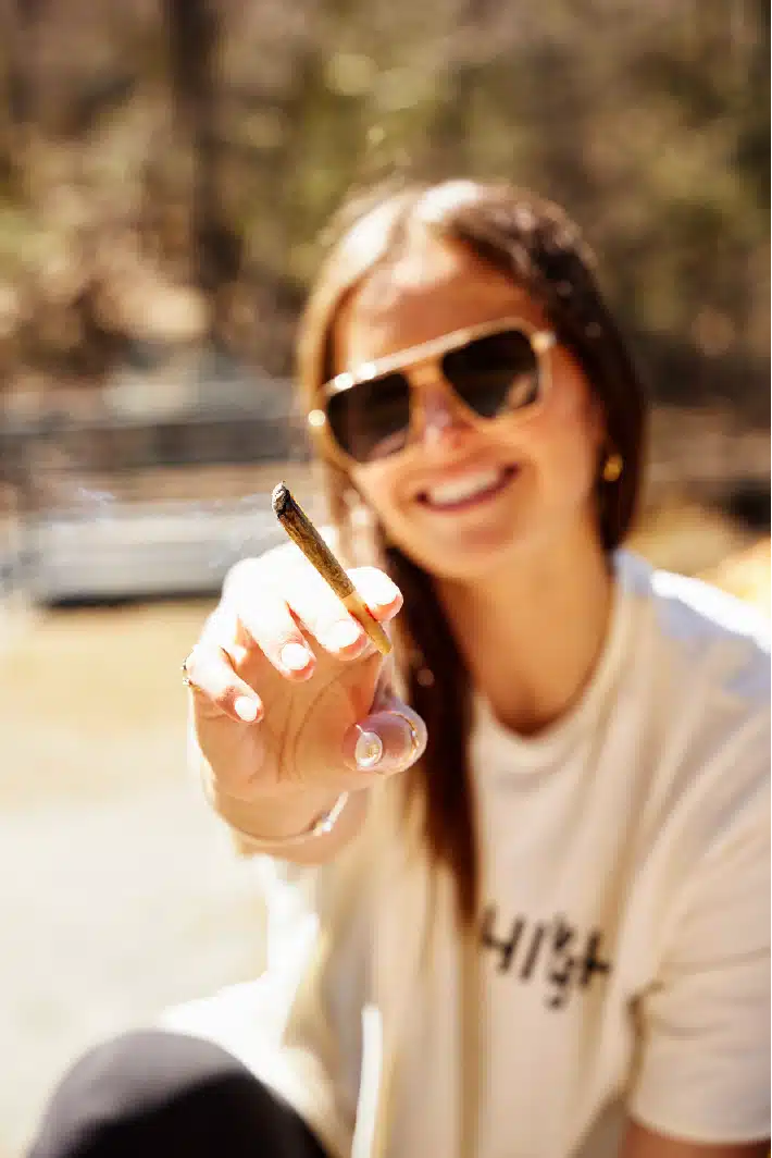 Woman extending hand with lit pre-roll