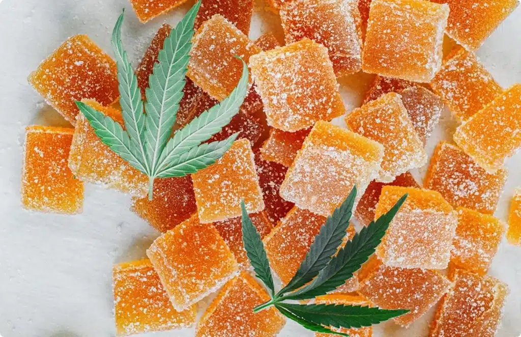 pile of orange gummies with cannabis leaves