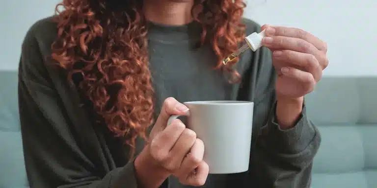 Woman using a dropper to add a tincture to her cup