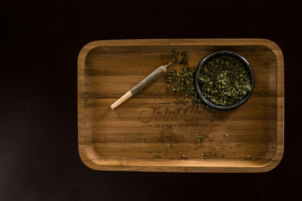 Pre-rolled joint and cannabis on a wooden tray
