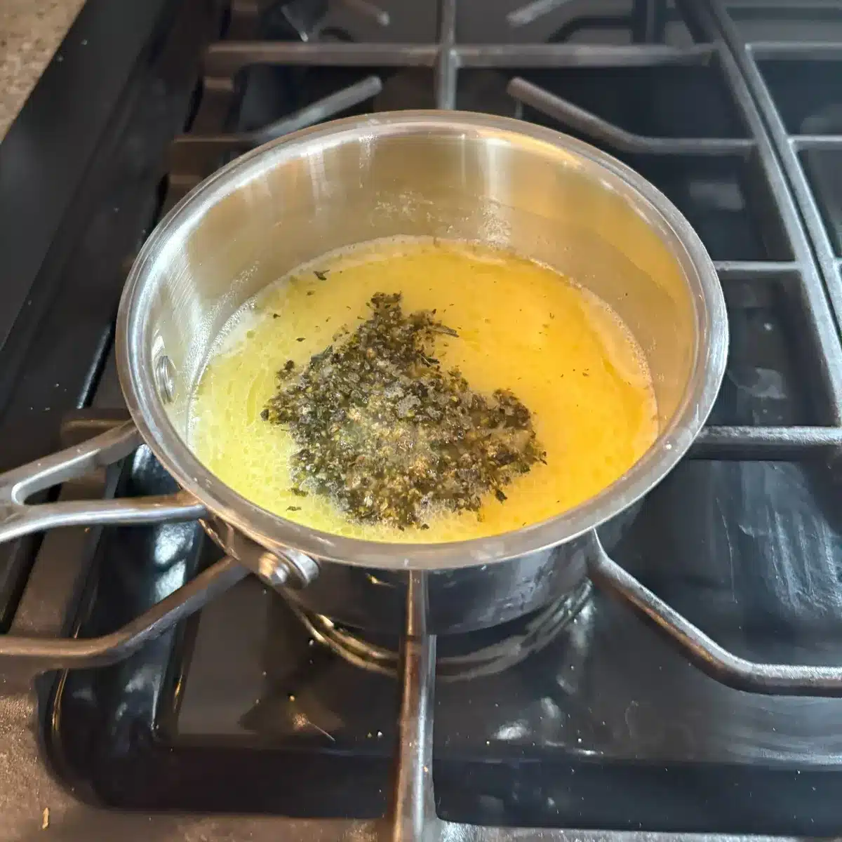 Cannabis pieces and melted butter in a saucepan on stovetop