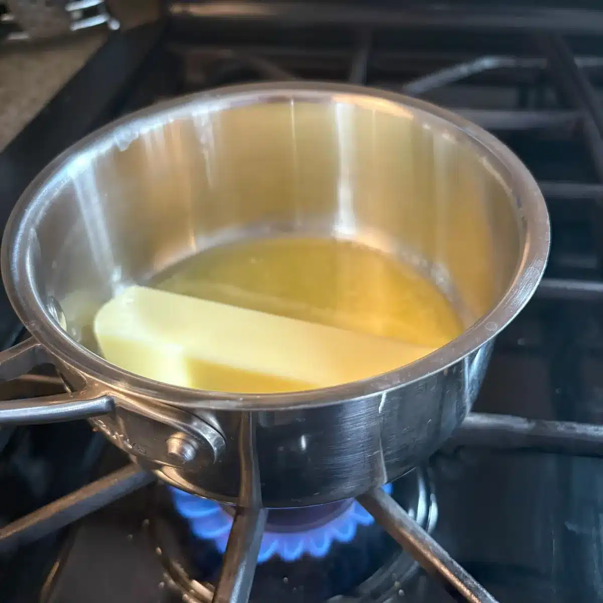 Partially melted stick of butted in a saucepan on stovetop