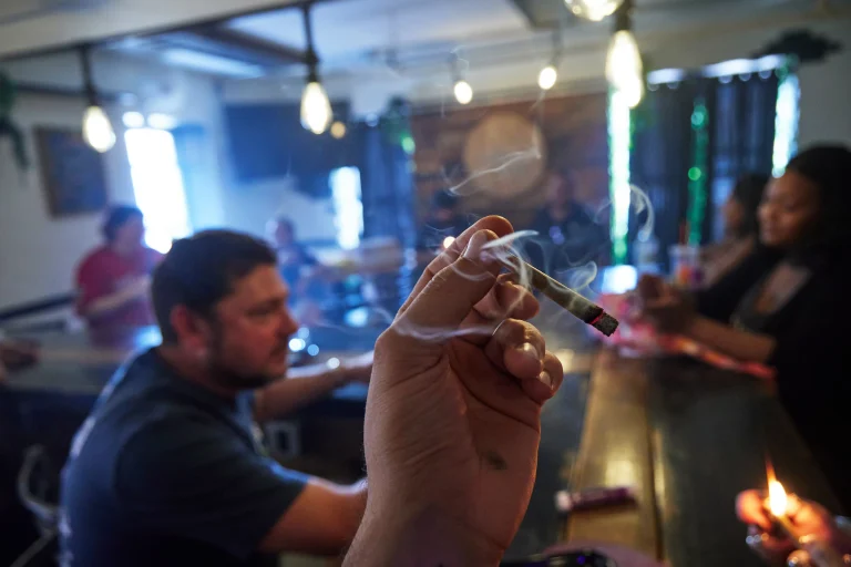 closeup of a hand holding a lit pre-roll